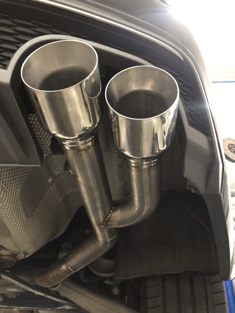 Two open mouth pipes, under car
