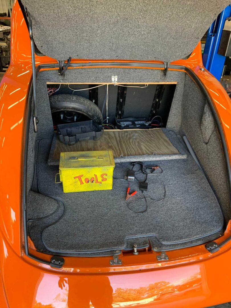 A yellow tool box in the trunk of an orange car