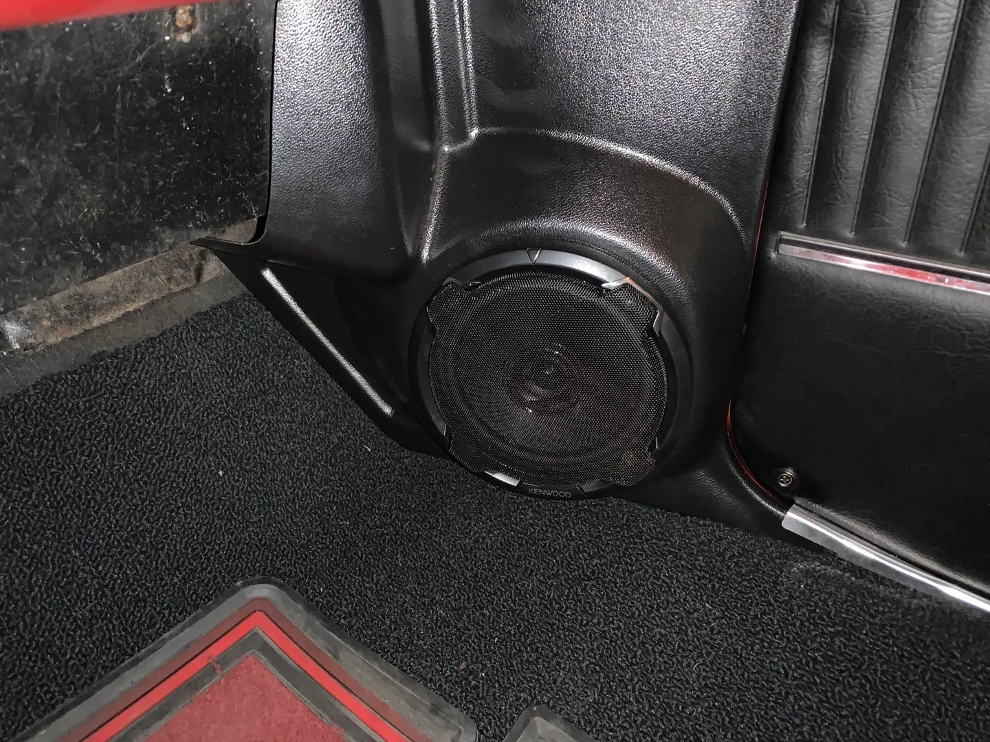 A black stereo speaker for a red vintage car